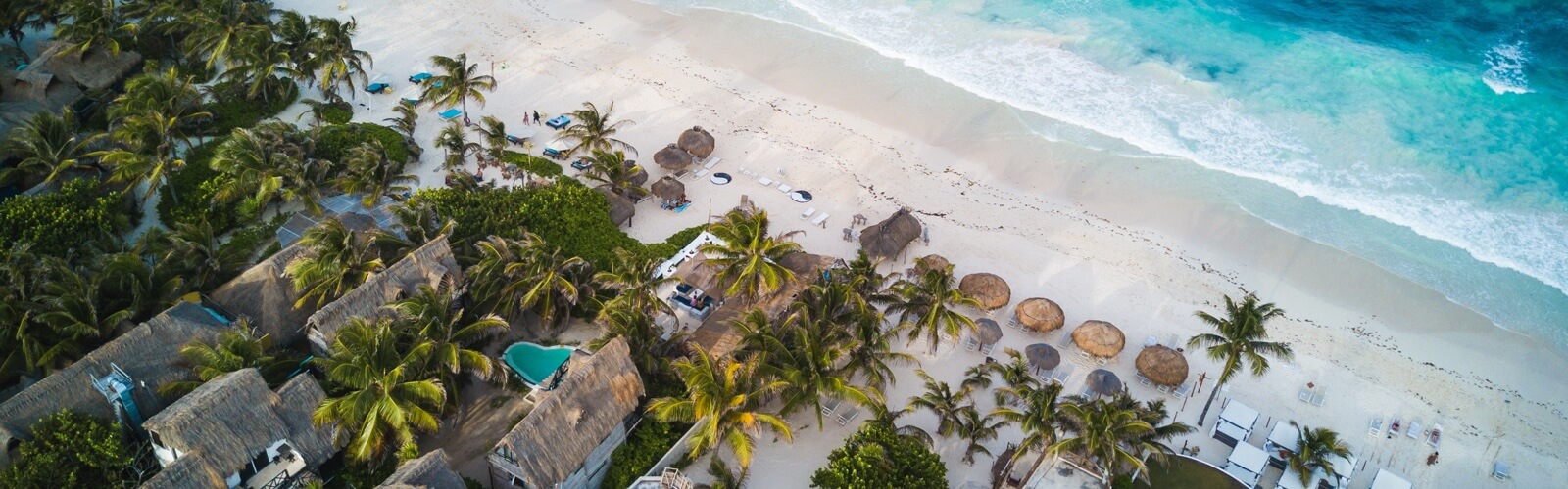 overhead view of beach houses and palm trees on a sandy beach