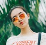 headshot of woman wearing reflective sunglasses in front of palm tree