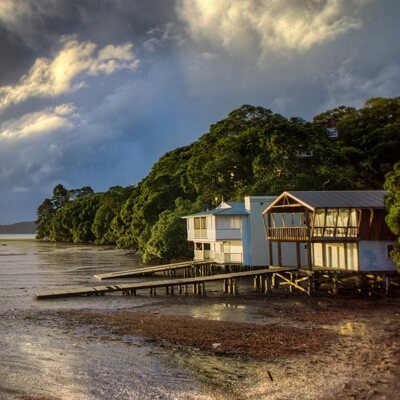 landscape view of small white beach house on beach, with deck leading into the ocean